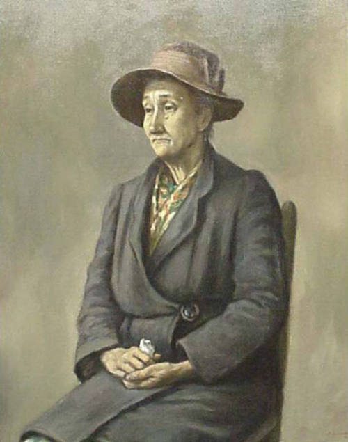 An oil painting of an older woman seated in a plain chair wearing a gray knee length coat, flor…