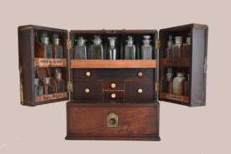 A mahogany medicine chest with two front doors containing two labeled shelves each, five drawer…