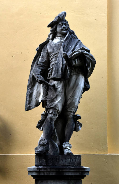 A standing male wearing a floppy cap and a cloak over pantaloons and a waistcoat with his prope…