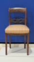 One of a pair of side chairs featuring swan neck back splats and striped cushions.