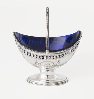A silver oval sugar basket on a pedestal base with a cobalt blue glass liner and an engraved bo…