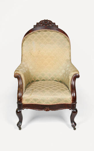 A stuffed Victorian-era armchair in the Rococo Revival style, including a carved crest rail dep…