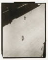 A bird's eye view of a bicyclist in the middle of the road and two figures walking on the top r…