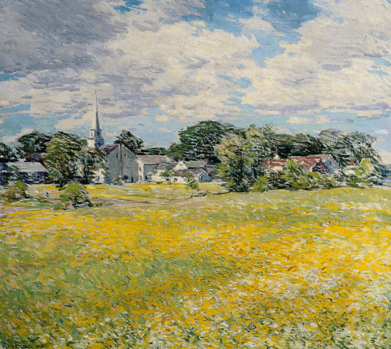A view across a field that is yellow and light green, to a sketchily composed town dominated by…
