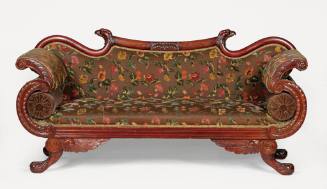 A carved mahogany sofa featuring American eagle details, including carved heads on each corner …