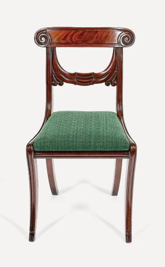 One of four carved mahogany side chairs.  Each chair exhibits a tablet crest rail having volute…