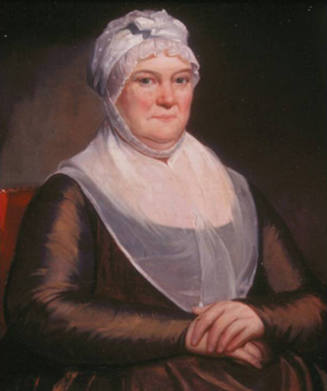 A  half-length portrait of a middle-aged, plump woman wearing a brown dress with a white collar…