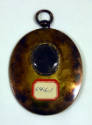 The back of the pendent showing a piece of the sitter's hair. 