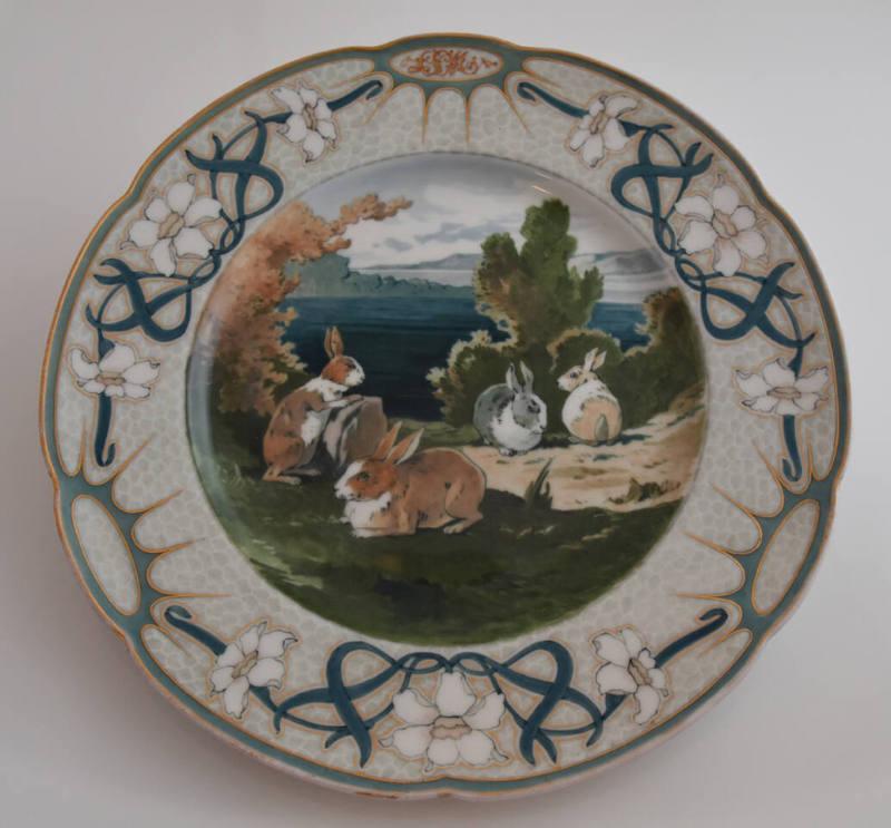 The fifteenth plate features a gray rim with three clusters of white flowers with long blue lea…