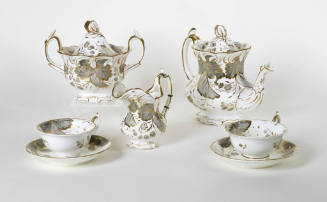An eighteen-piece tea service decorated with gray berries and leaves trimmed in gold.