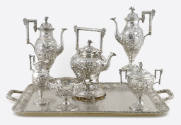 A seven-piece tea and coffee service embellished with repousse flowers and alpine village scene…