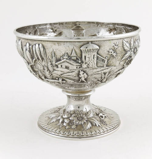 A silver waste bowl embellished with a repousse alpine scene.