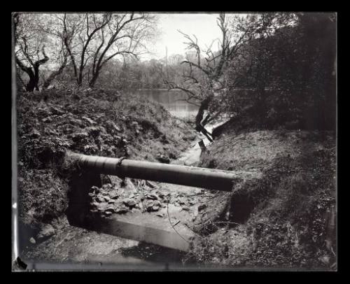 A pipe crosses a shallow river bed.