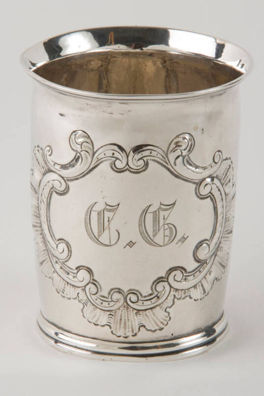 A silver beaker with a scalloped and c-scroll engraved medallion.