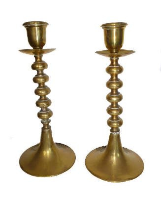 A pair of brass candlesticks with round bases and five knobs on the column.