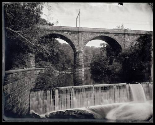 A bridge crosses over the Schuylkill River and a small waterfall.