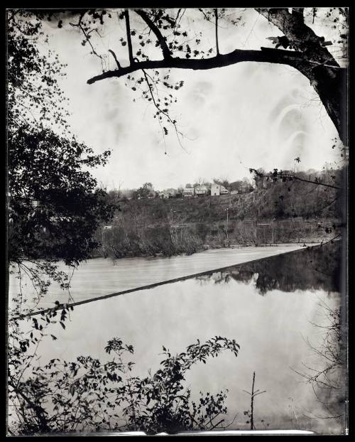 This landscape image shows the Scotts Mill Dam on the James River with foliage to the left of t…