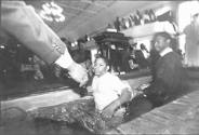 A black and white photograph of a young man being helped out of a baptismal font.