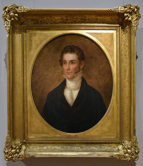 Half-length portrait of a young man with light brown curly hair and mutton chops wearing a brow…