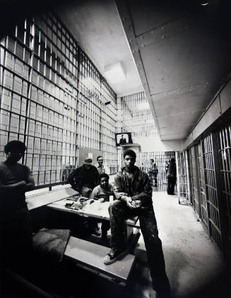 Individuals sitting around a table in a prison block.