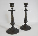 A pair of bronze candlesticks, heavily embossed with a foliate design.