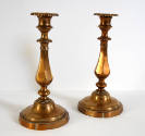 A pair of copper candlesticks with detached bobeches, and round, fluted bases.