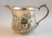 A cream pitcher with an S-shaped handle with foliate repoussé decoration by an eagle.  