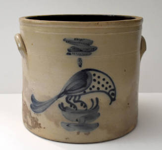 A cream-colored crock painted with a blue bird on the side.