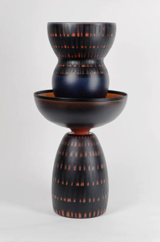 A black and red sculpture composed of bowl-shaped tiers.
