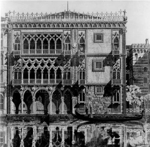 A heavily ornamented Venetian building mirrored in the glassy surface of the canal in the foreg…
