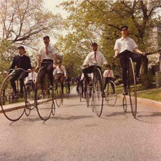 A group of people biking on old fashioned bicycles.