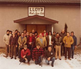 A group of hunters standing in front of a brown building.