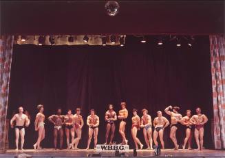 A group of body builders standing on a stage.