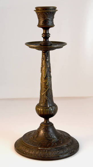 One of a pair of bronze candlesticks, heavily embossed with a foliate design.
