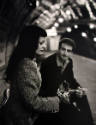 A black and white photograph of a man and a woman sitting in a subway station.