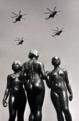 A black and white photograph of three bronze nude female figures from a ground perspective with…