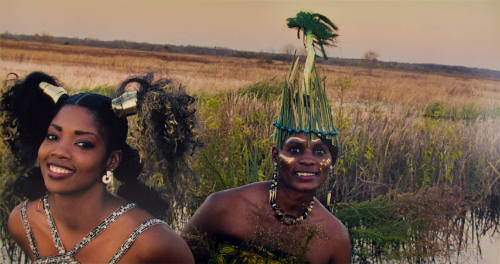 Two women - one with pigtails adorned with gold cuffs and the other wearing facial paint and a …