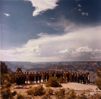 A group of park rangers standing by a cliff edge overlooking the canyon. 