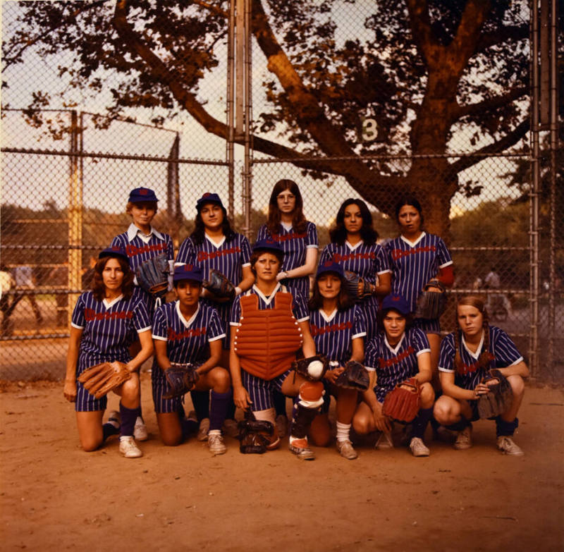 A women's softball team wearing blue striped uniforms and staged in two rows. 