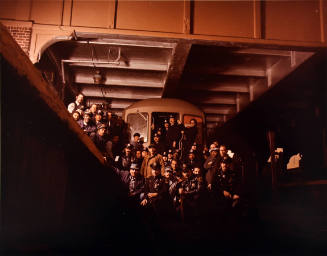 A group of conductors standing subway tracks in front of a train.