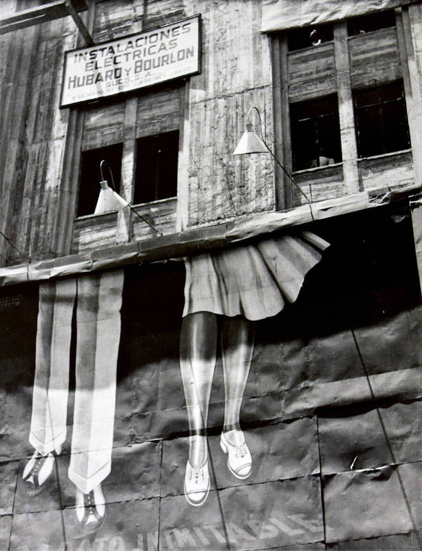 A black and white photograph of a billboard depicting a pair of male and female legs on the sid…