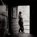 A black and white photograph of a couple embracing in an open doorway.