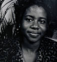 A black and white photograph of a young woman in a leopard print patterned garment in front of …