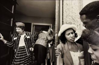 A black and white photograph of a woman in a striped suit exiting a church.