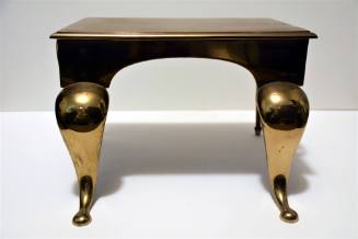 A polished cast brass stand with cabriole legs.