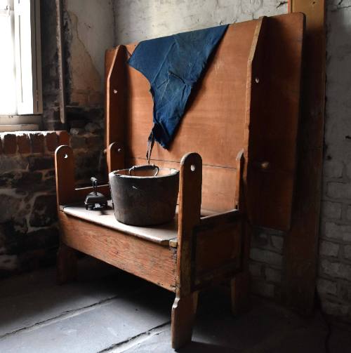 A plain pine hutch or ironing table with a tilt-top and bench on four legs.