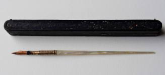 A pen with a carved brass nib attached to a mother-of-pearl handle in a hinged leather case lin…