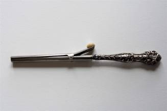 A silver-plated glove stretcher with a floral repousse design on the handle and a mother-of-pea…