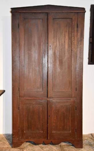 A kitchen cupboard with a triangular pediment and two sets of doors. 