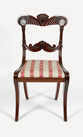 A Regency-style side chair with a carved back and upholstered in pink and white striped fabric.